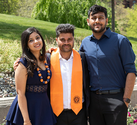 Class of 2023 graduate stands with friends and family