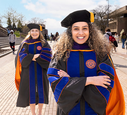 Two doctoral degree recipients stand together on the Einhorn Family Walk